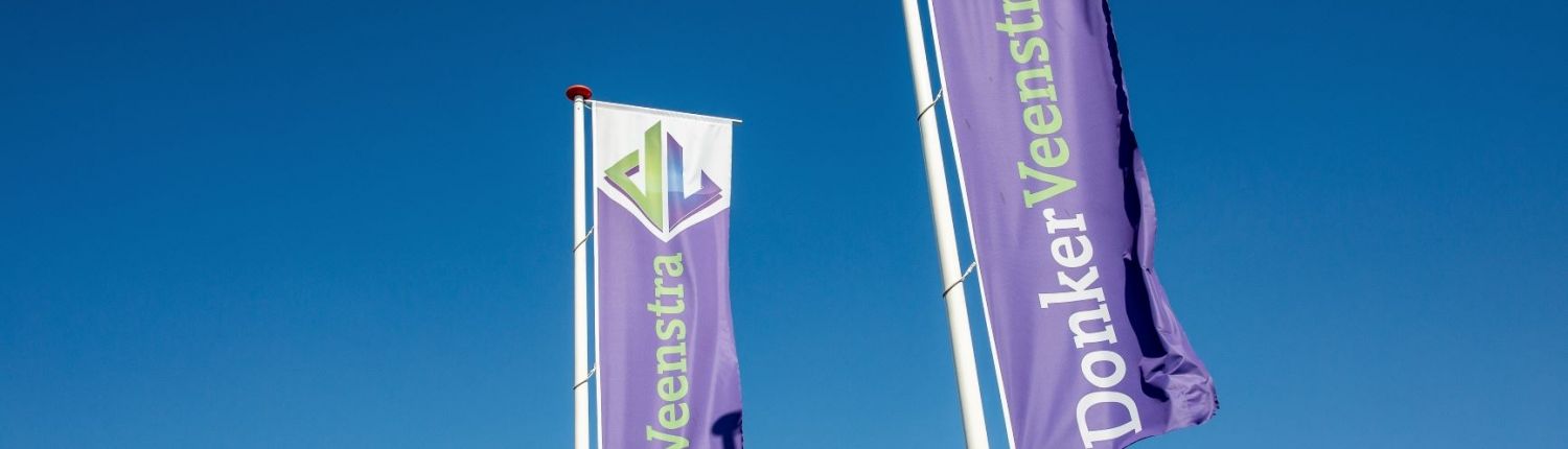 Twee paarse vlaggen met het bedrijf DonkerVeenstra erop. Bovenaan het groen en blauwe logo van DonkerVeenstra. Blauwe lucht als achtergrond.